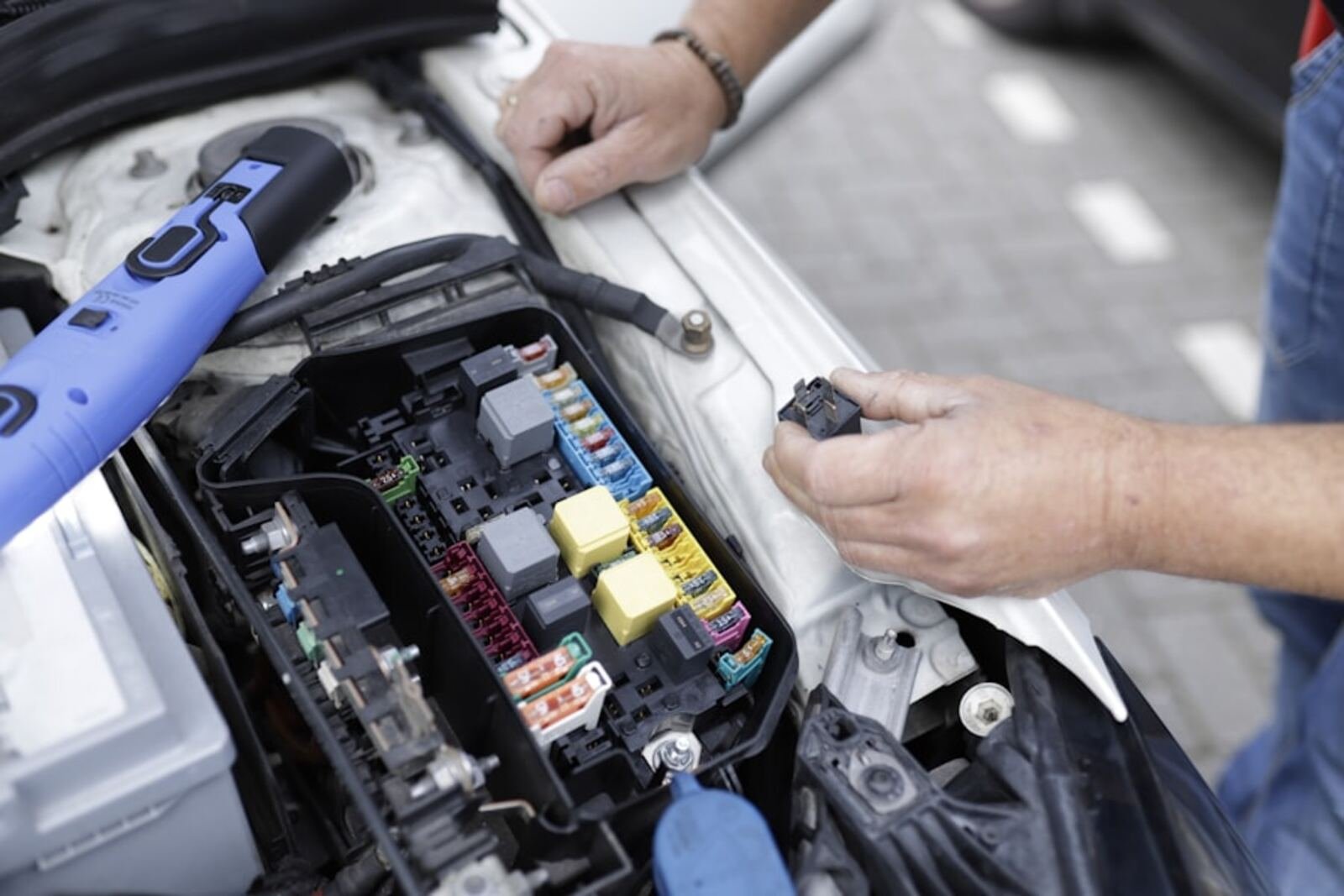 Technicien installant un boîtier GPS dans le compartiment moteur d'un véhicule